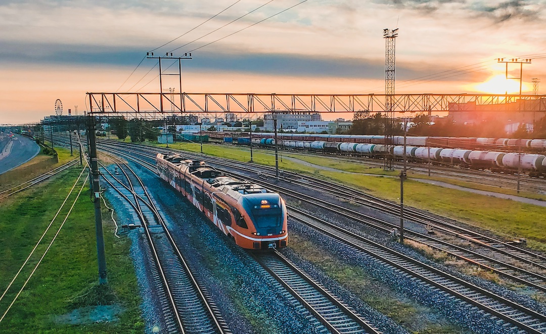 Oranž elektrirong raudteel, taustaks loojuv päike