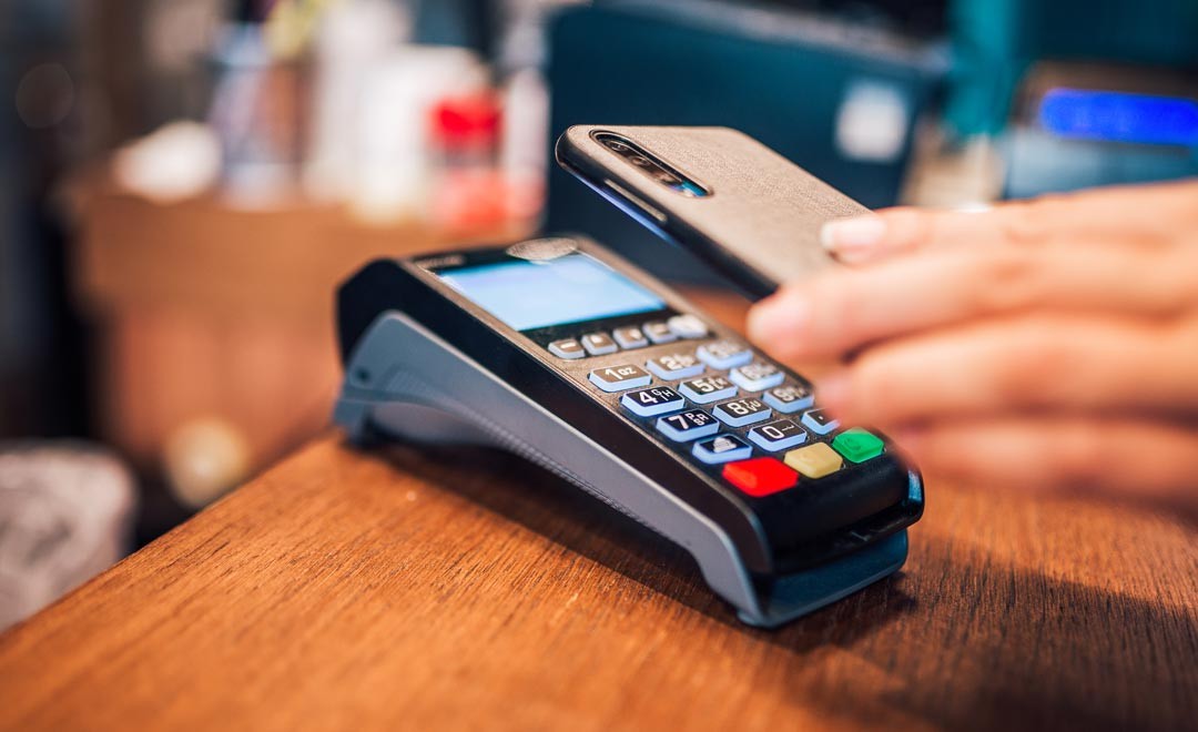 Viipemakse terminal ja inimese käsi telefoniga makseks viipamas. 