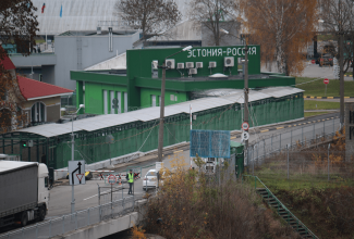 Narva-Ivangorodi piiripunkt, esiplaanil maantee, tagaplaanil roheline piiripunkti hoone. 